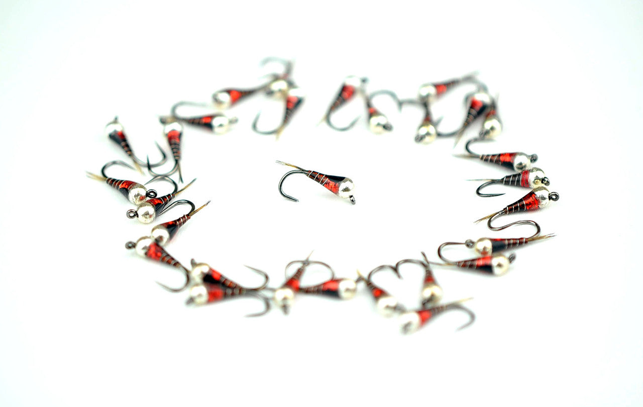 A circle of red-and-silver Perdigon jig nymphs on white — slim, resin-coated, tungsten-beaded